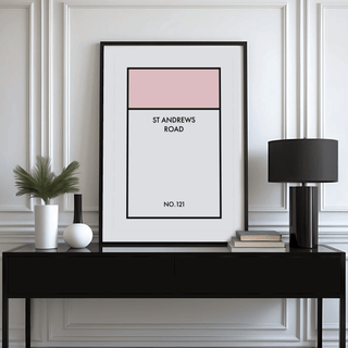 Framed Street Name Family Personal wall art with pink and white blocks on a black console with lamp and books