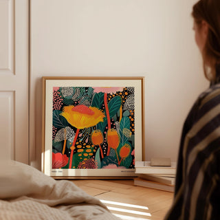 Floral prints for framing leaning on floor with vibrant yellow and orange petals beside stacked books
