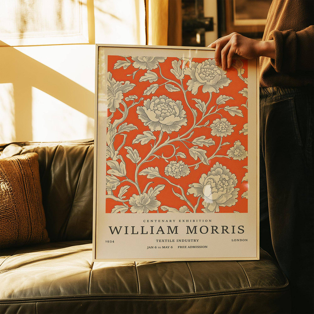 Framed Vintage Flower Art of cream peony flowers on bright orange background held above a brown leather sofa