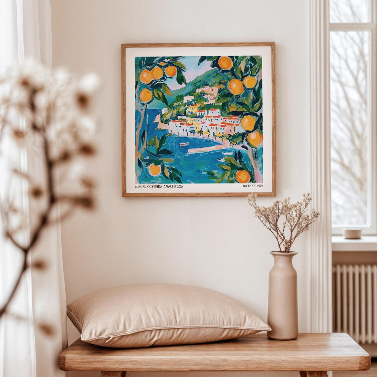 Amalfi wall art of a coastal village with oranges in blue and orange tones above a wooden table with cushion and vase