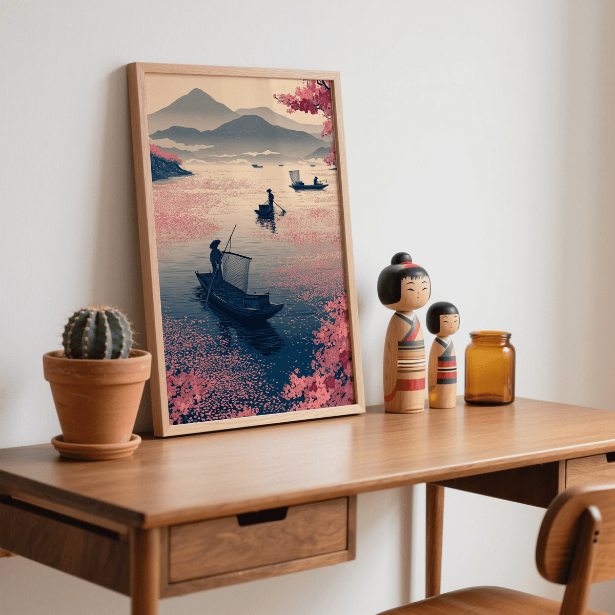 Framed Zen Fishing Poster with fishing boats and pink floral touches on a desk with wooden doll figurines and cactus