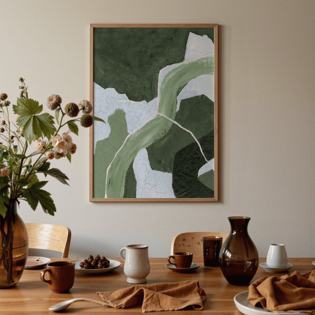 Abstract green art print with flowing shapes in green shades hanging above a dining table with crockery and a vase