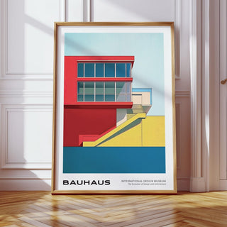 Framed Mid Century Modern Art Print showing a minimalist bauhaus building in red yellow and blue tones leaning on a wooden floor