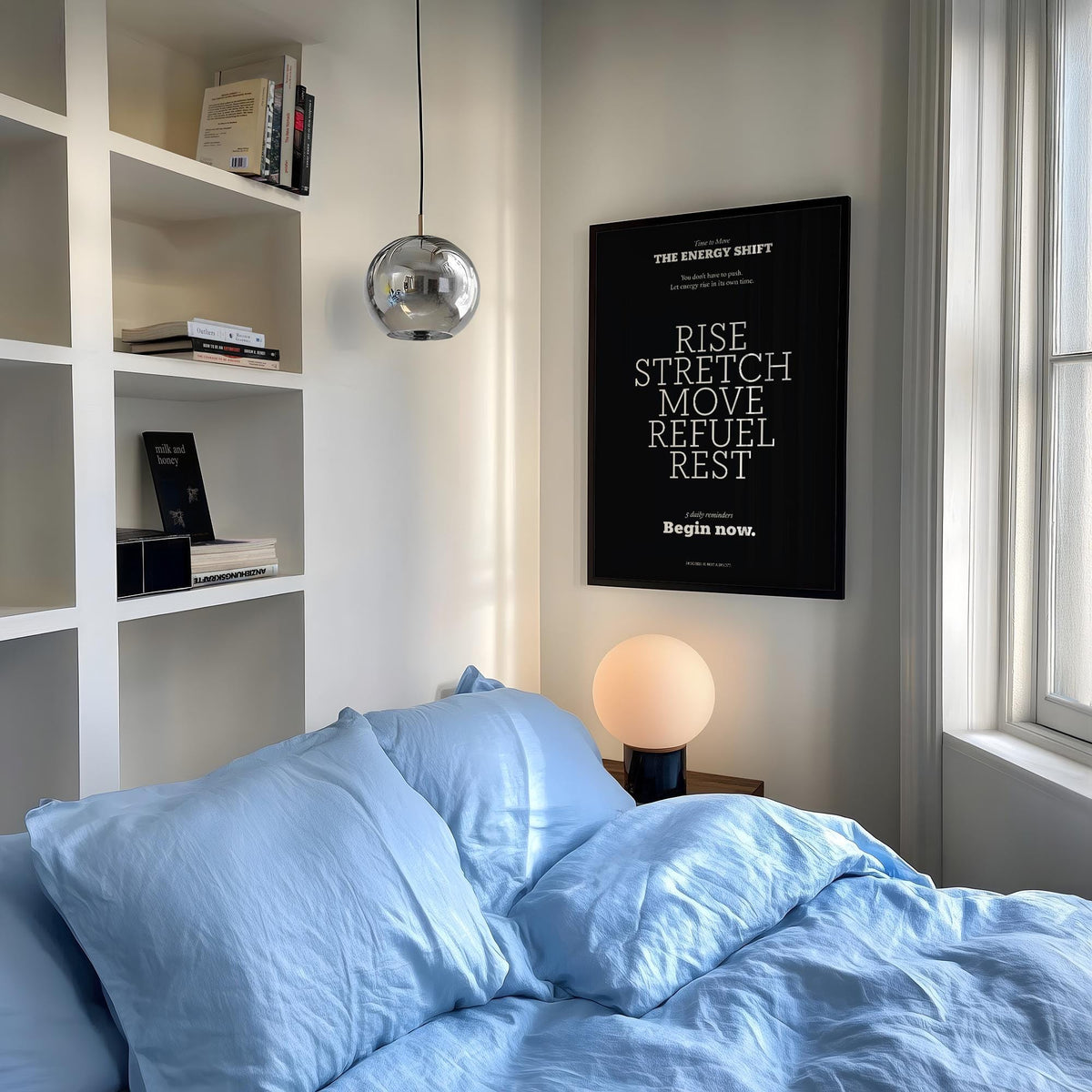Motivational posters with quotes framed print with white text on black above a bedside table lamp and blue bed