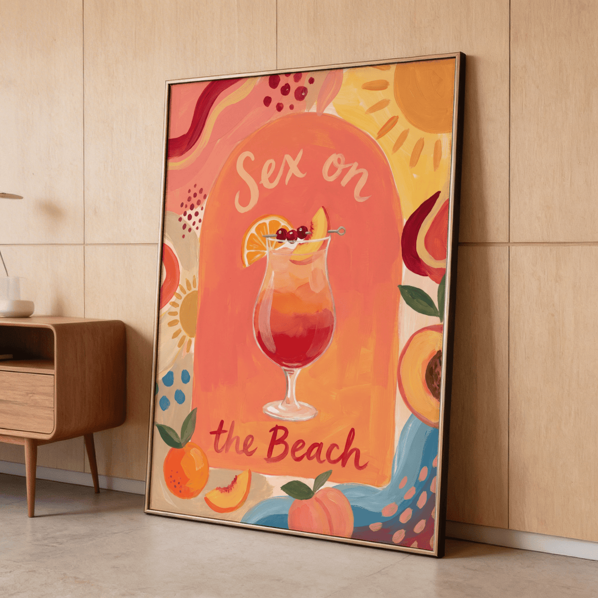 Framed Colorful Drink Poster leaning against a wooden wall with vivid orange and yellow tones and fruit illustrations