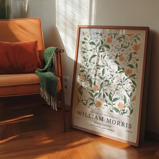 Print leaning on floor with vintage prints flowers in orange white and green near an orange chair with a green throw