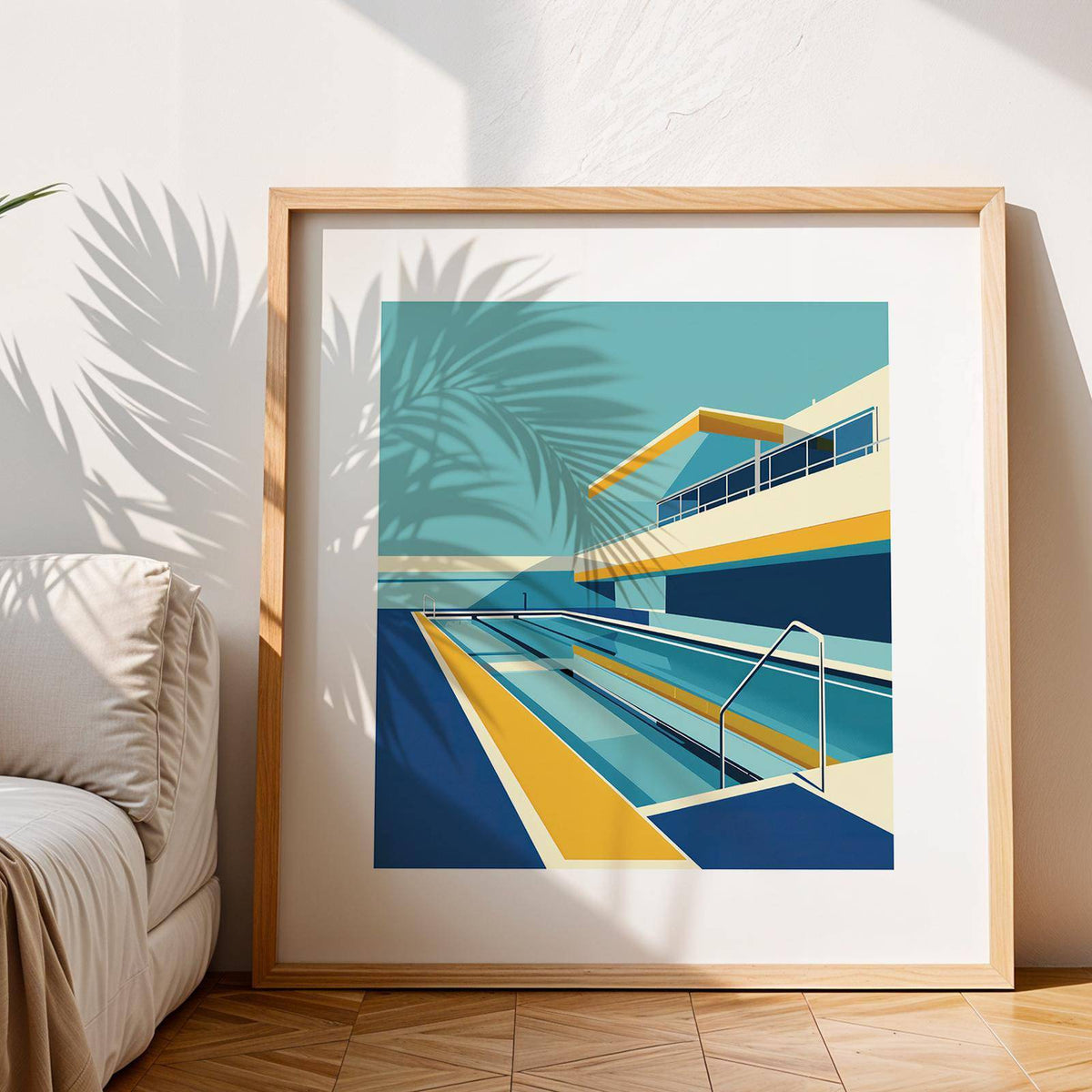 Framed Poolside Art showing a modern poolside scene in blue yellow and cream leaning on a wooden floor with a sofa