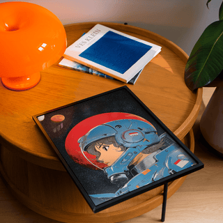 Framed Space Girl art close-up showing a female astronaut with blue helmet on a wooden table with orange lamp