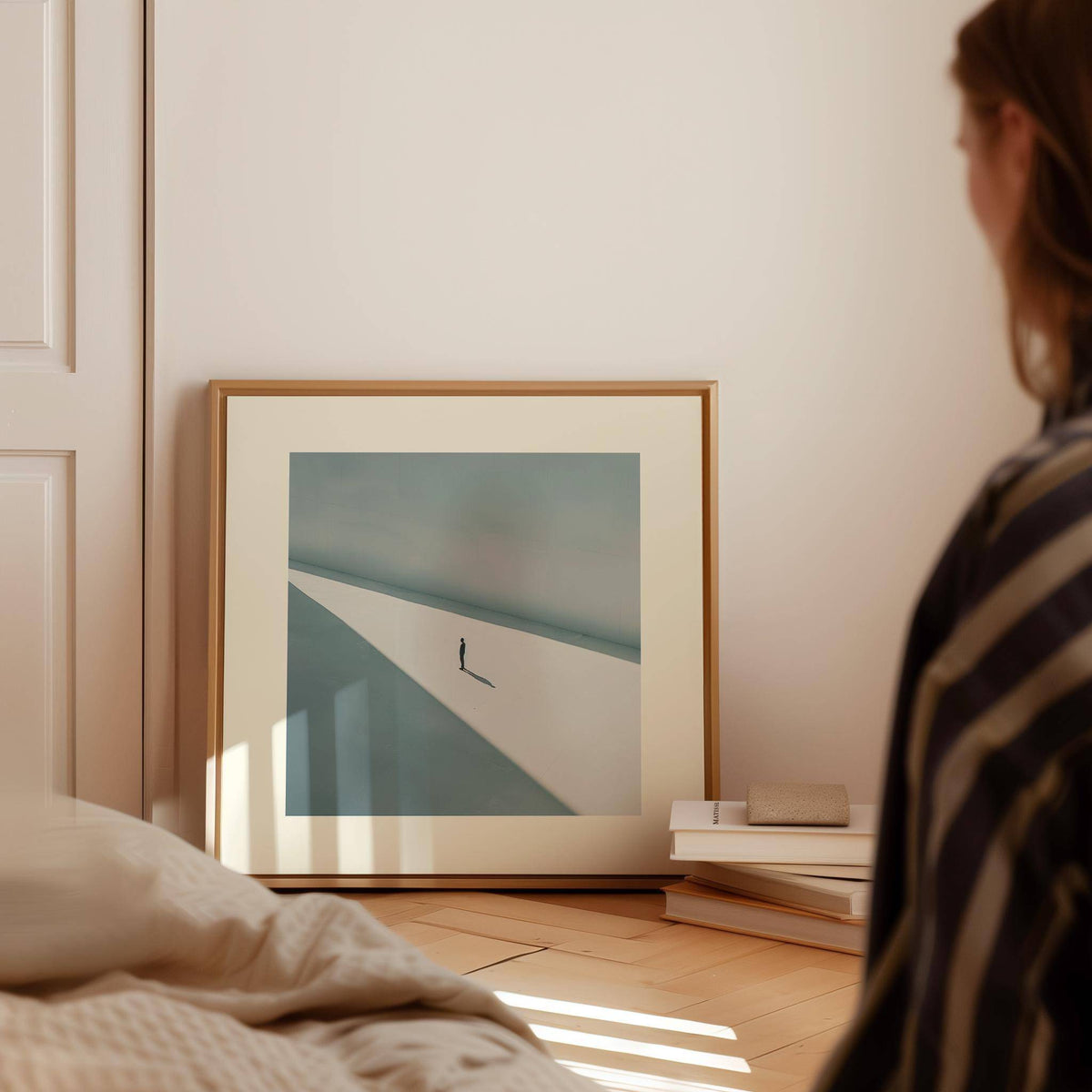Art Prints Square print of solitary person in shadow in muted greys leaning on floor near books