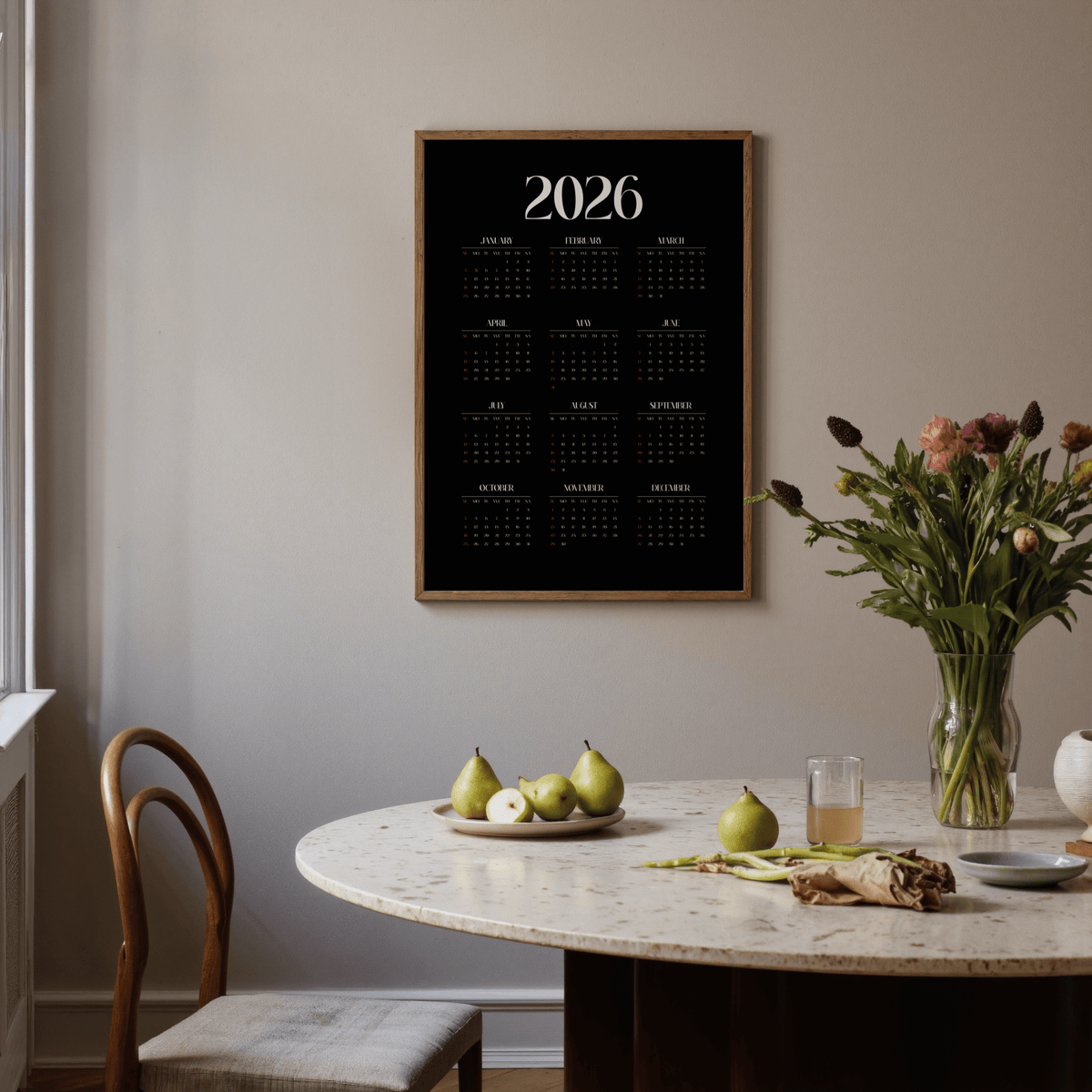 Modern Calendar Print hanging above a round dining table with pears and a vase of flowers