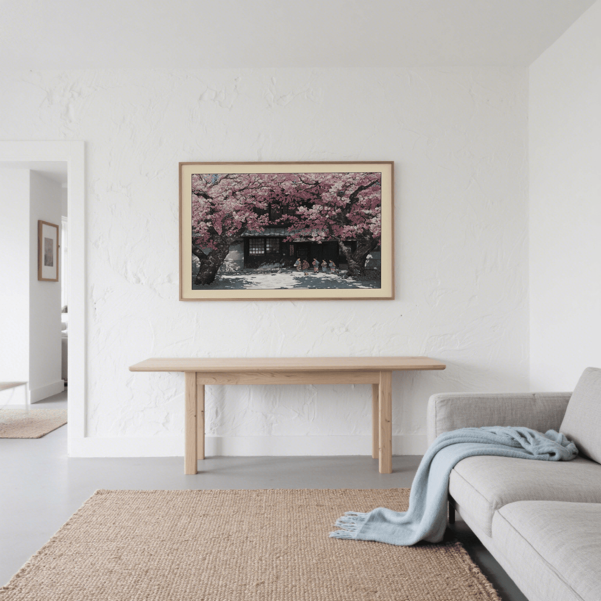 Print on a wall in a living room with a beige bench below showcasing cherry blossoms and children in soft pinks and blues