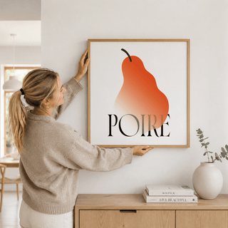Modern Pear Poster held on a wall showing orange and black pear design with typographic text and a vase on a sideboard