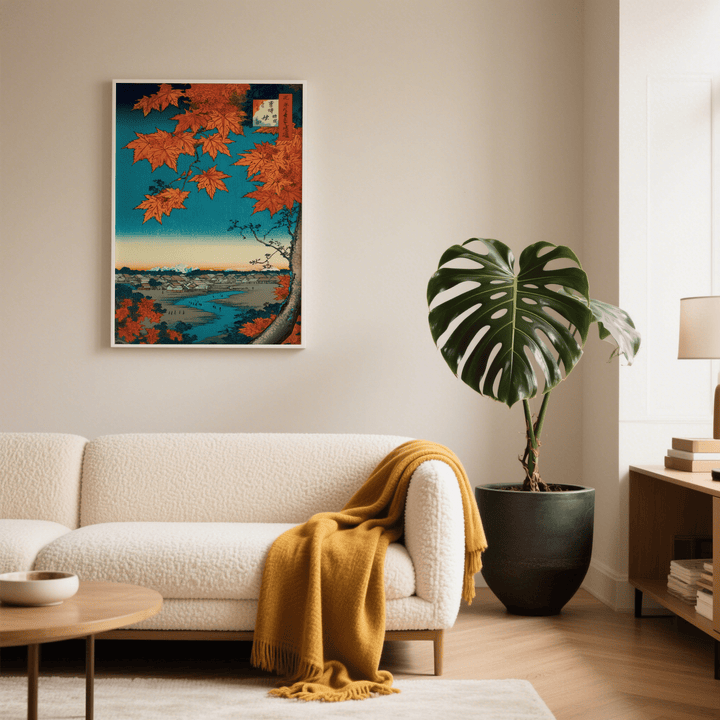 Japanese landscape art print with red maple leaves on a wall above a beige sofa with an orange throw