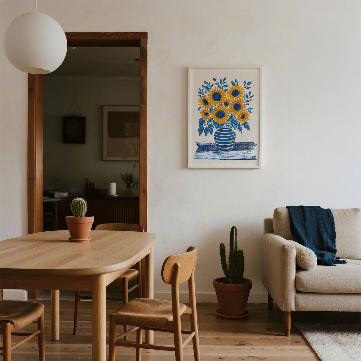 Sunflower Print hanging on wall above a wooden dining table with a small cactus plant