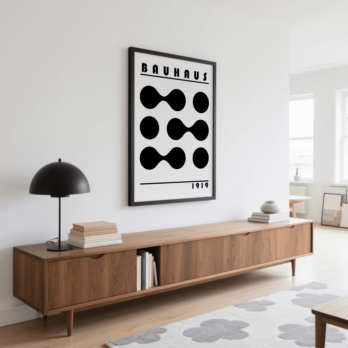 Framed minimalist geometric print with black abstract shapes above a wooden sideboard in a living room