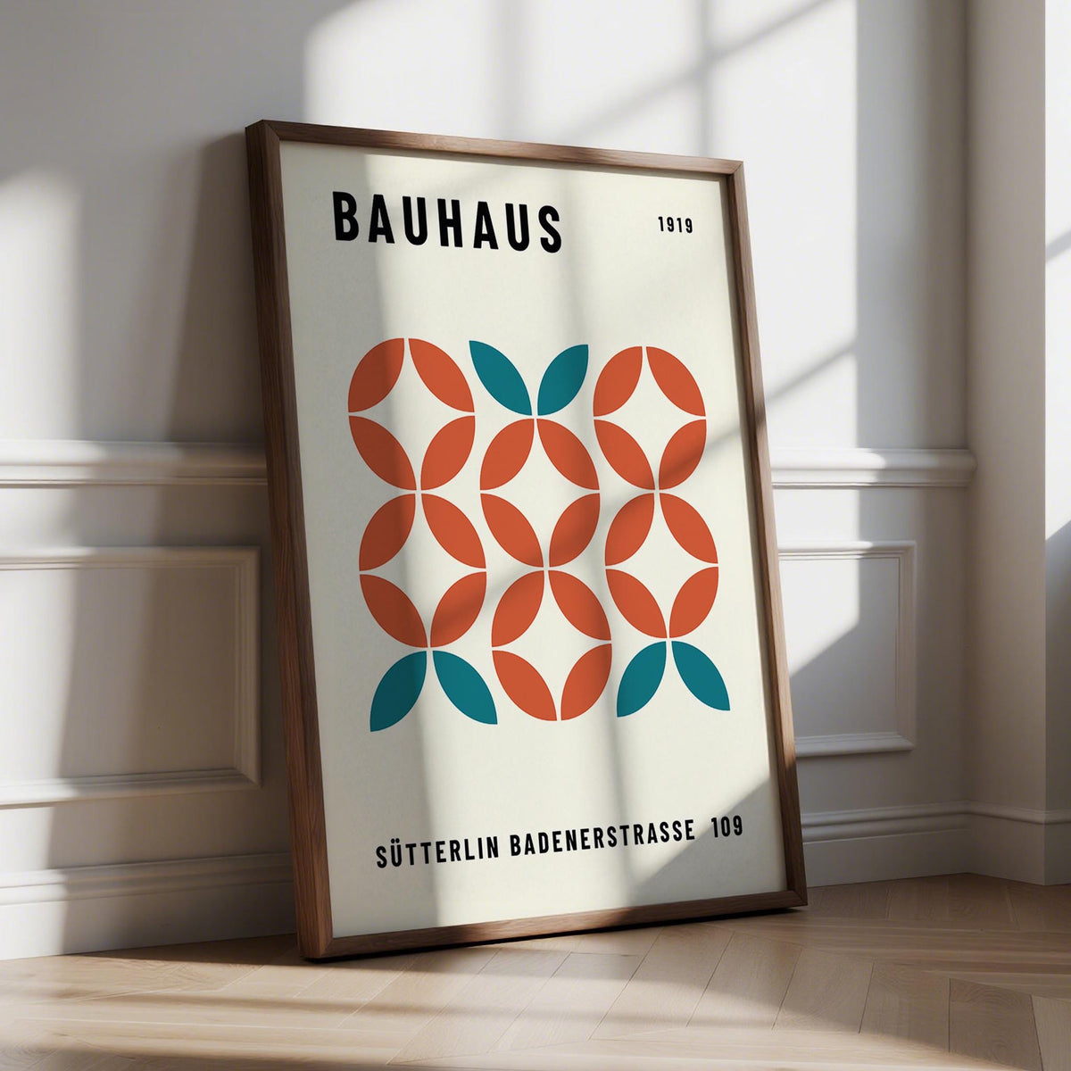 Print leaning on a floor featuring modern geometric wall art with teal and terracotta shapes and text