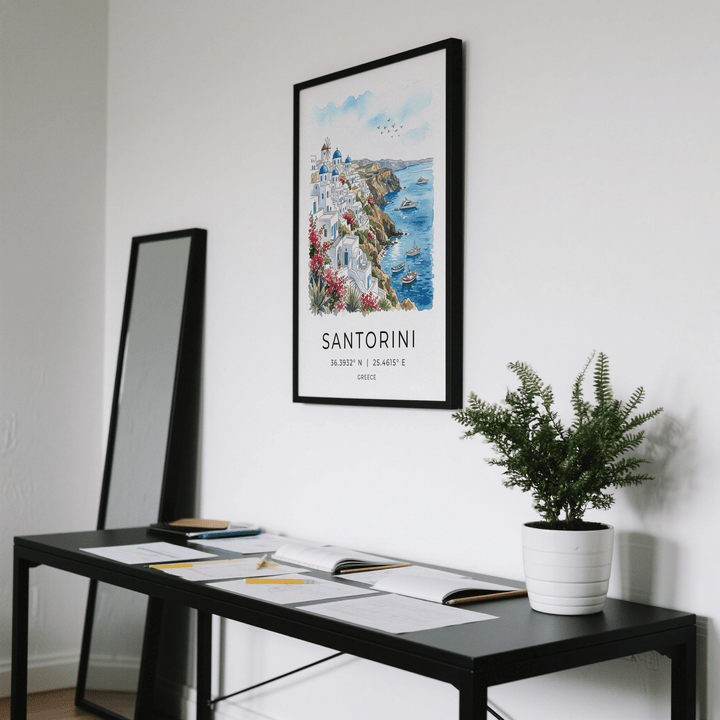 Santorini art print of a watercolour cliffside village with boats and blue sky above a black table with a plant pot