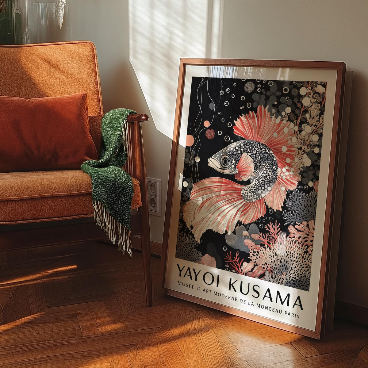 Print leaning on a floor next to an orange sofa with a green throw