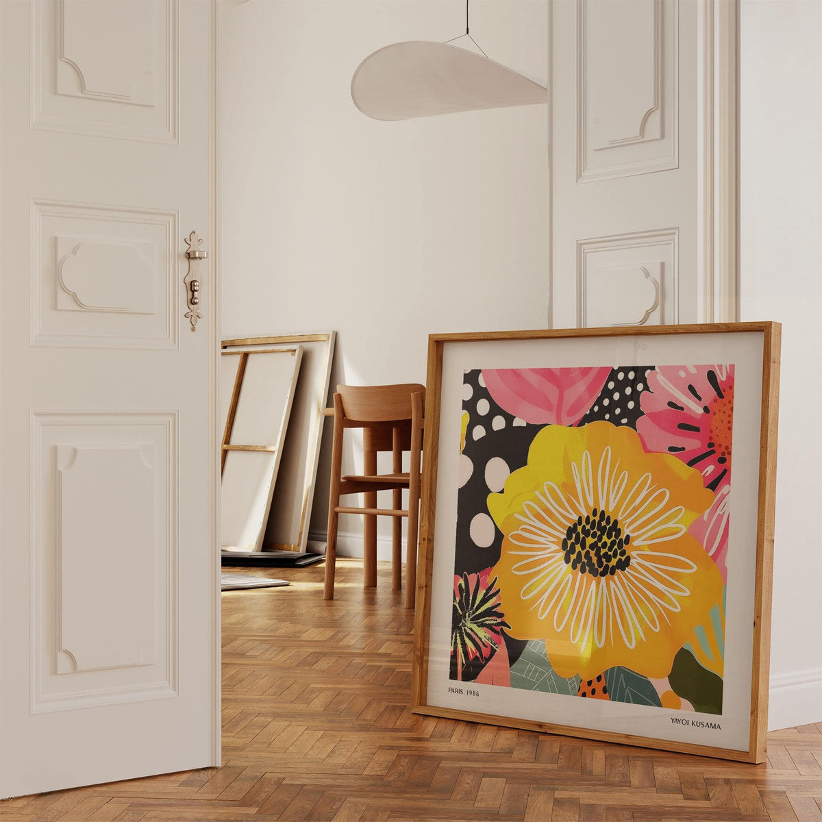 Flower Posters print leaning on floor with yellow and pink petals in room with wooden chair