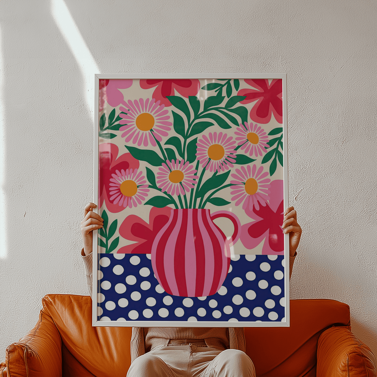 Framed Colorful Flower Art Print of pink daisies in a striped vase held by person on tan sofa