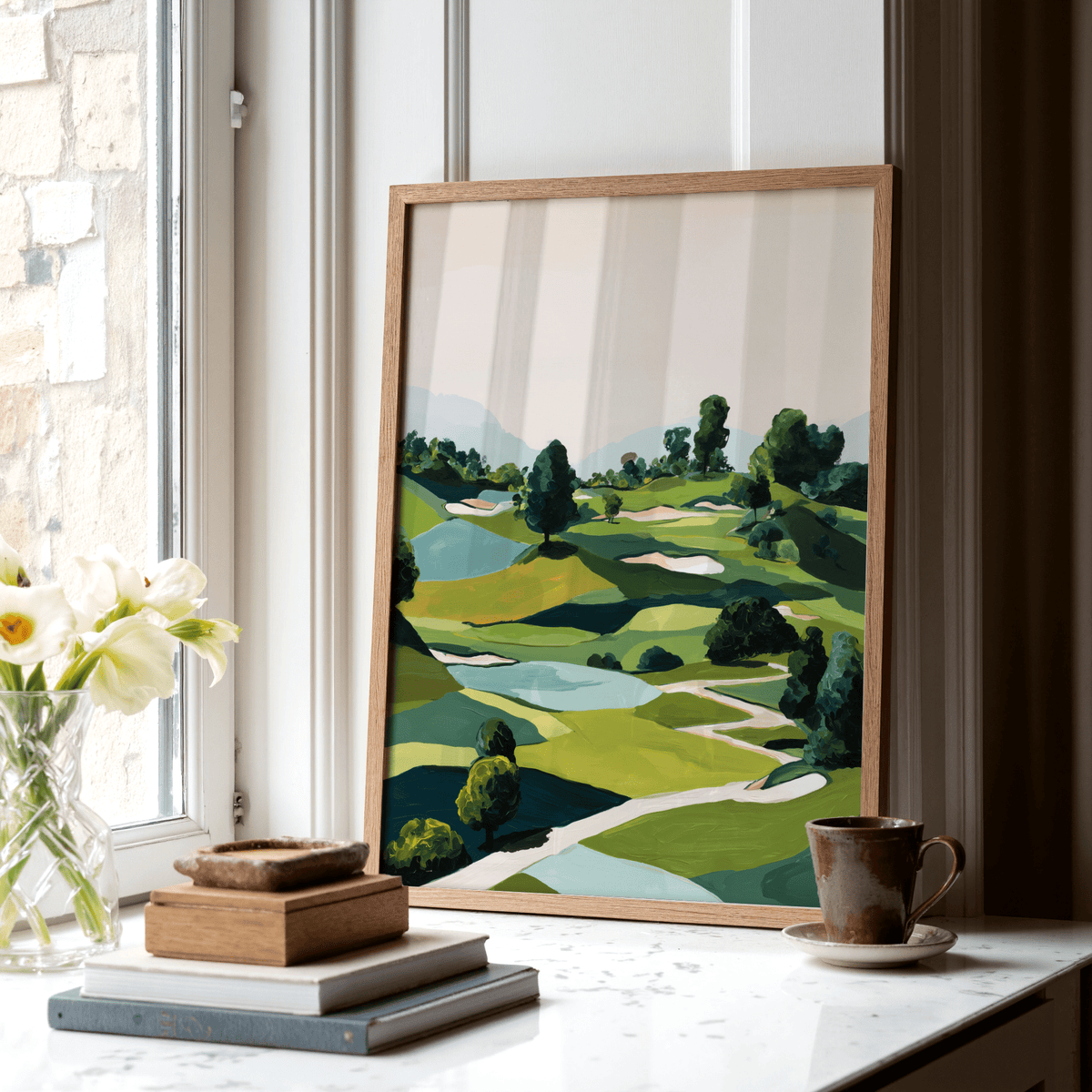 Framed Landscape Golfing Poster leaning on a shelf with books and a cup near a window