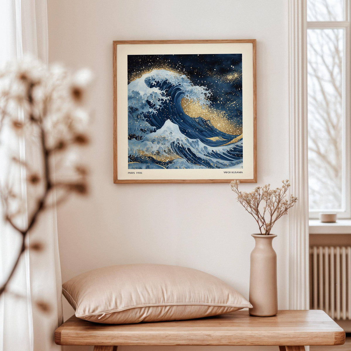 Wall art of the ocean showing a blue wave with gold splashes above a beige cushion on a wooden table