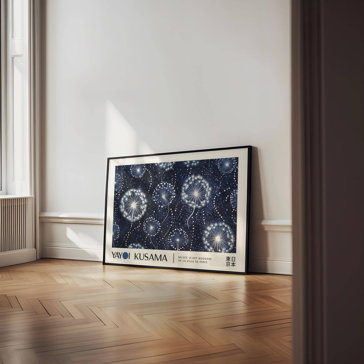 Landscape poster of dandelion seed heads in a black frame leaning on a parquet floor near a window