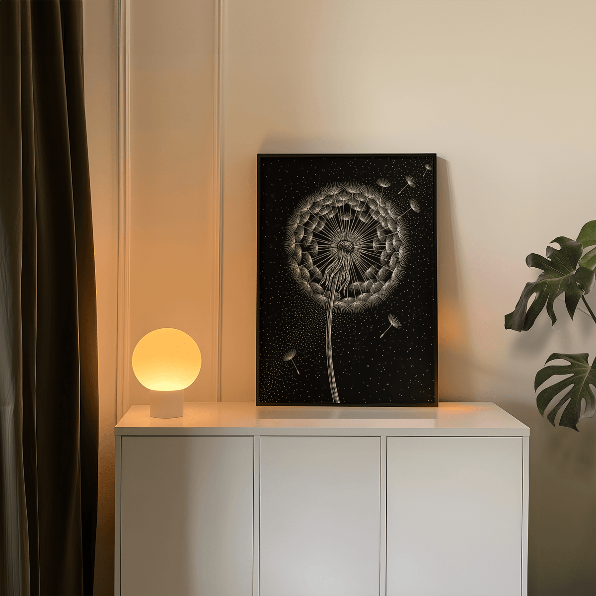 Print leaning on a white sideboard with a glowing orb lamp showing a minimalist black and white dandelion poster