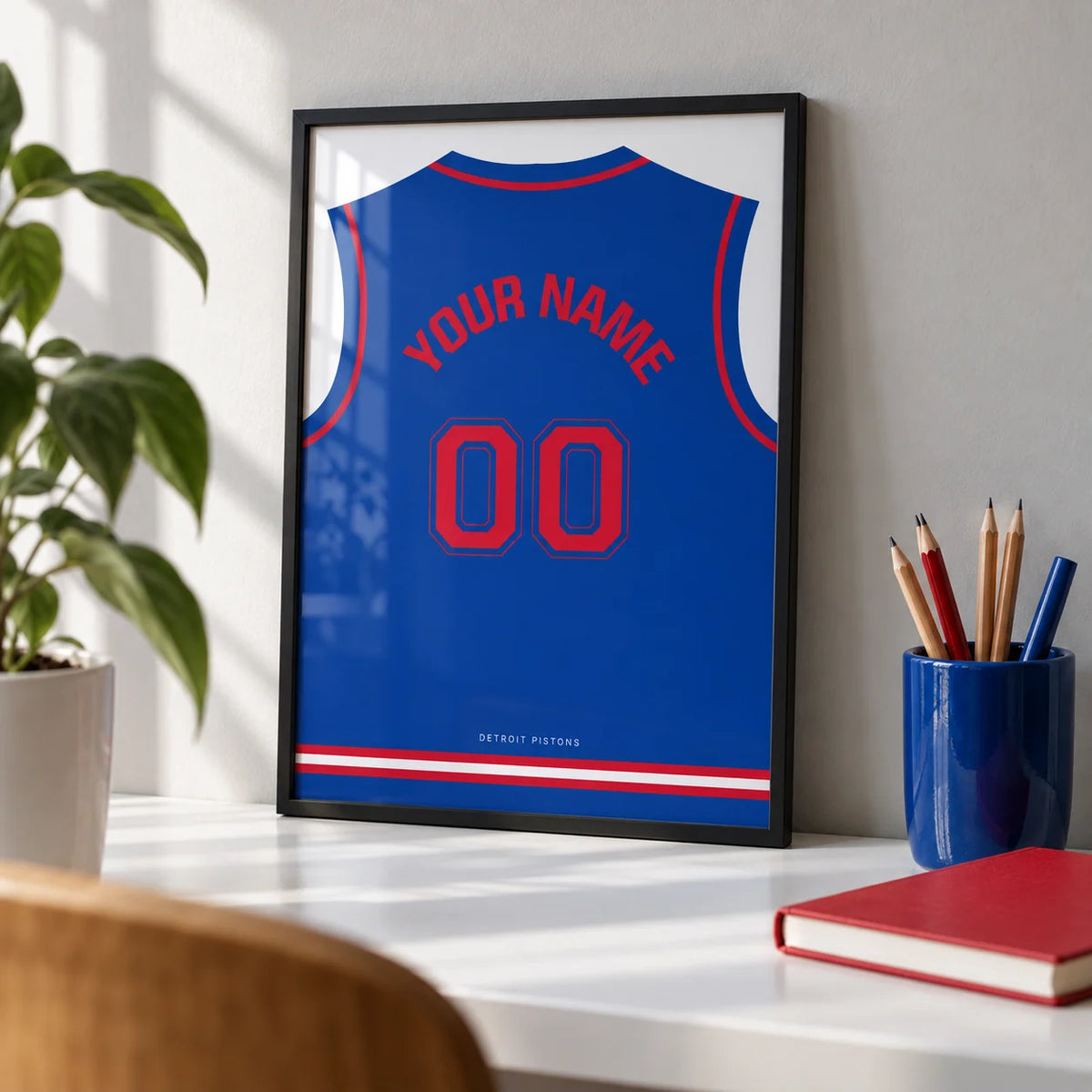 Basketball Jersey Poster in Blue with Red Number, a small A4 framed print leaning on a white desk