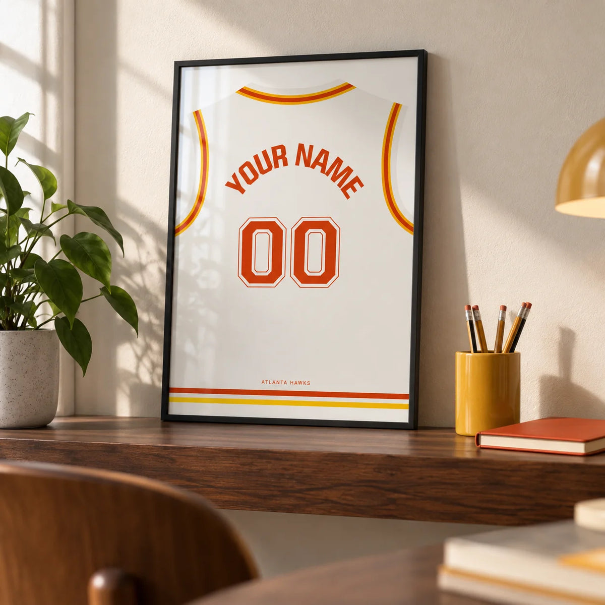 Basketball Jersey Poster in White with Red and Yellow Trim, a small A4 framed print leaning on a walnut shelf in a home office
