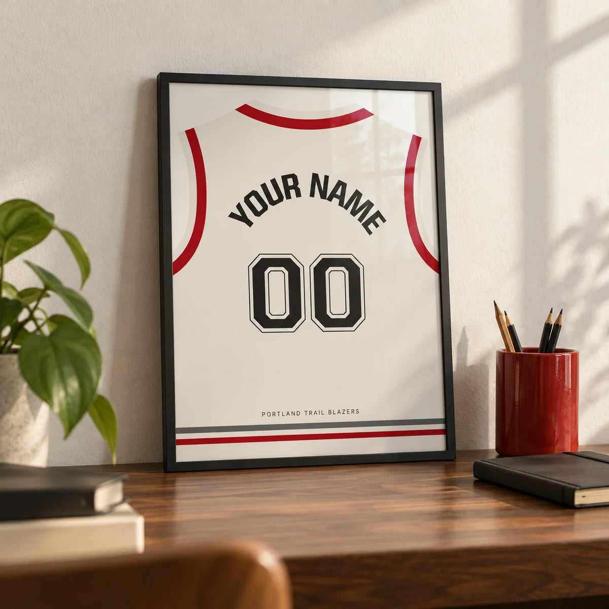 Basketball Jersey Poster in White with Red Sleeves and Black Number, a small A4 framed print leaning on a walnut desk