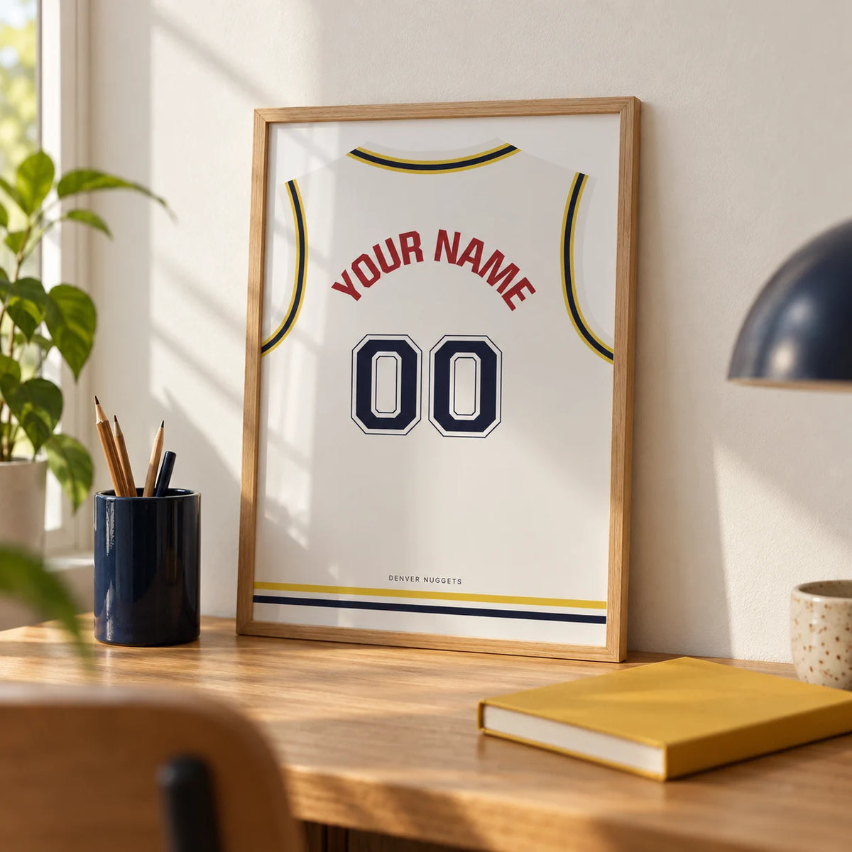 Basketball Jersey Poster in White with Yellow and Navy Trim, a small A4 framed print leaning on an oak desk