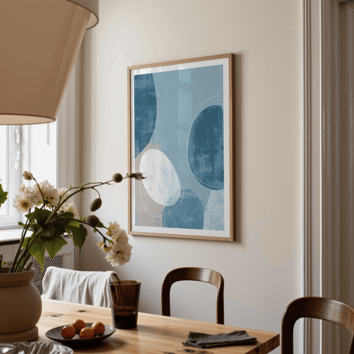 Contemporary pattern poster of abstract ocean shapes in blue and beige above a dining table with flowers