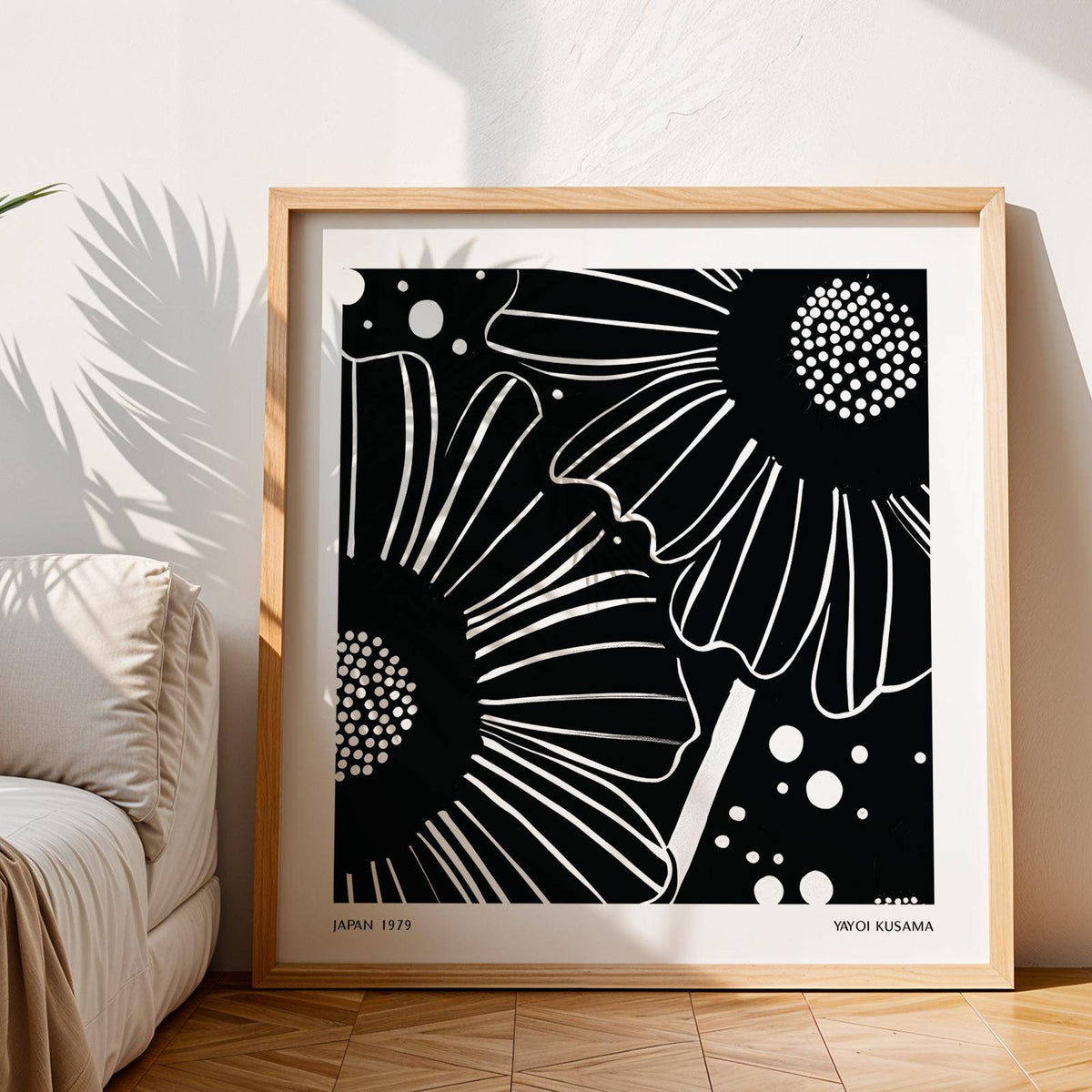 Black White Floral Art print leaning on wooden floor with sunlight and sofa nearby