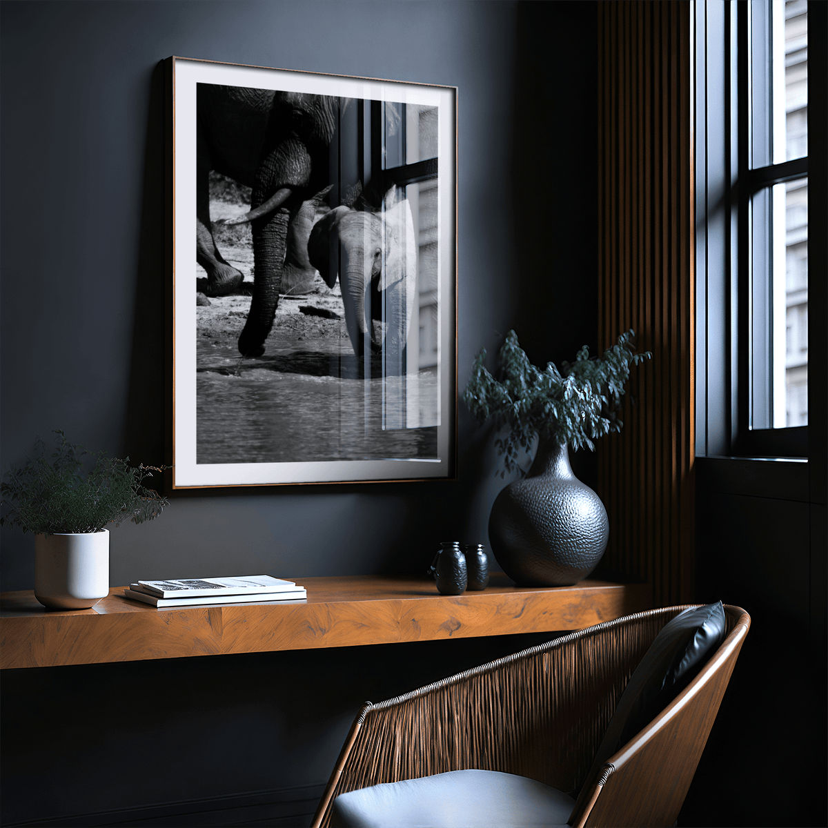 Nature art print of baby elephant with adults in black and white above a wooden shelf in a dark room