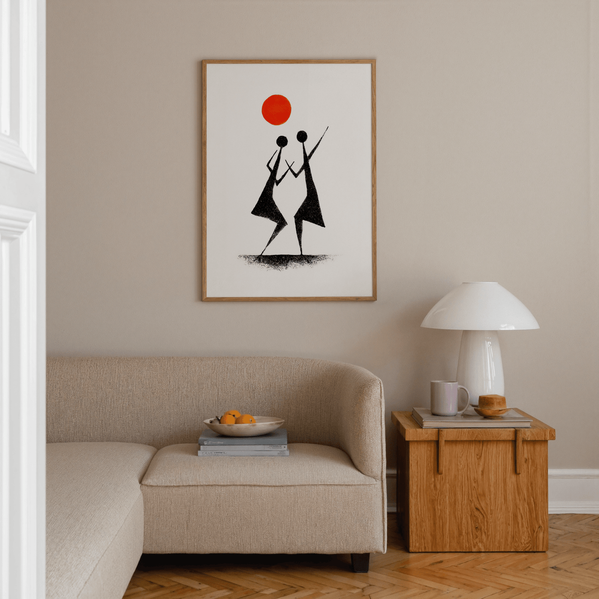 Warli Folk Art Print of tribal dancers in black with an orange sun above a beige sofa in a living room