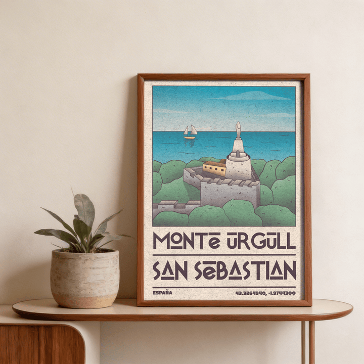 Framed San Sebastian art print of Monte Urgull statue and sea in soft greens and blues on a table with a plant
