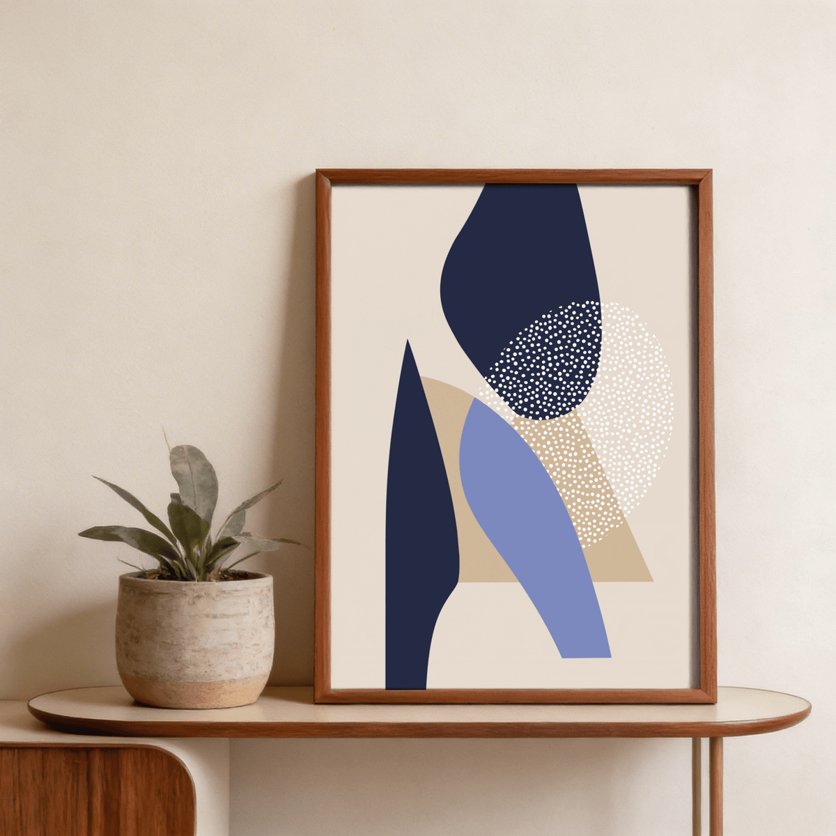 Framed Abstract Art Poster with blue and beige abstract shapes on a table with a small plant