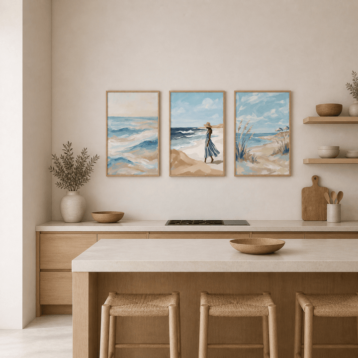 Coastal wall art set above kitchen counter featuring three minimalist watercolour beach scenes with blue and beige tones and a plant on