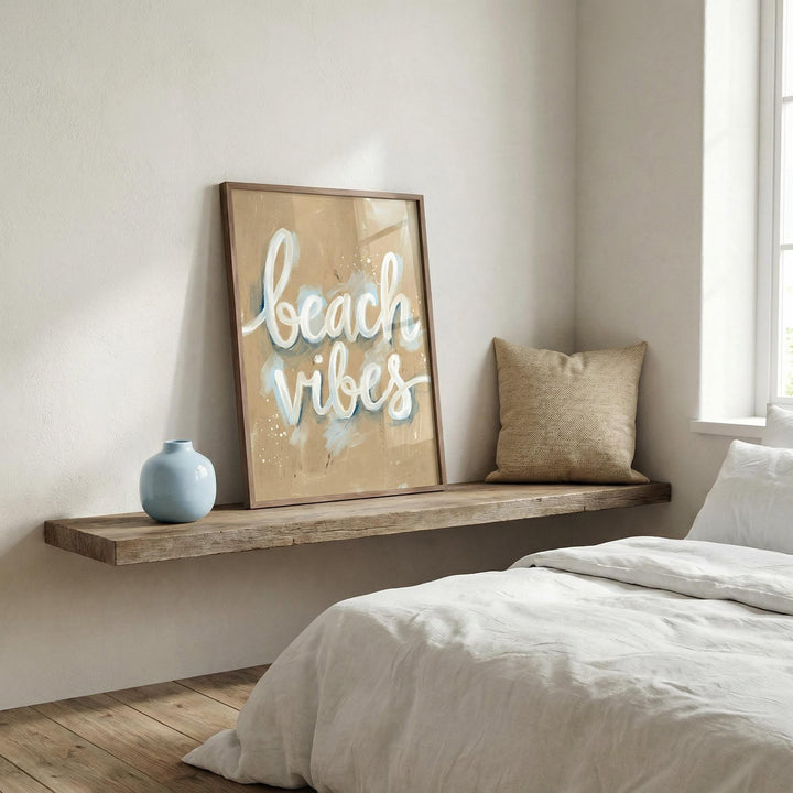 Print leaning on a wooden shelf with beach vibes text in white and blue with a blue vase nearby