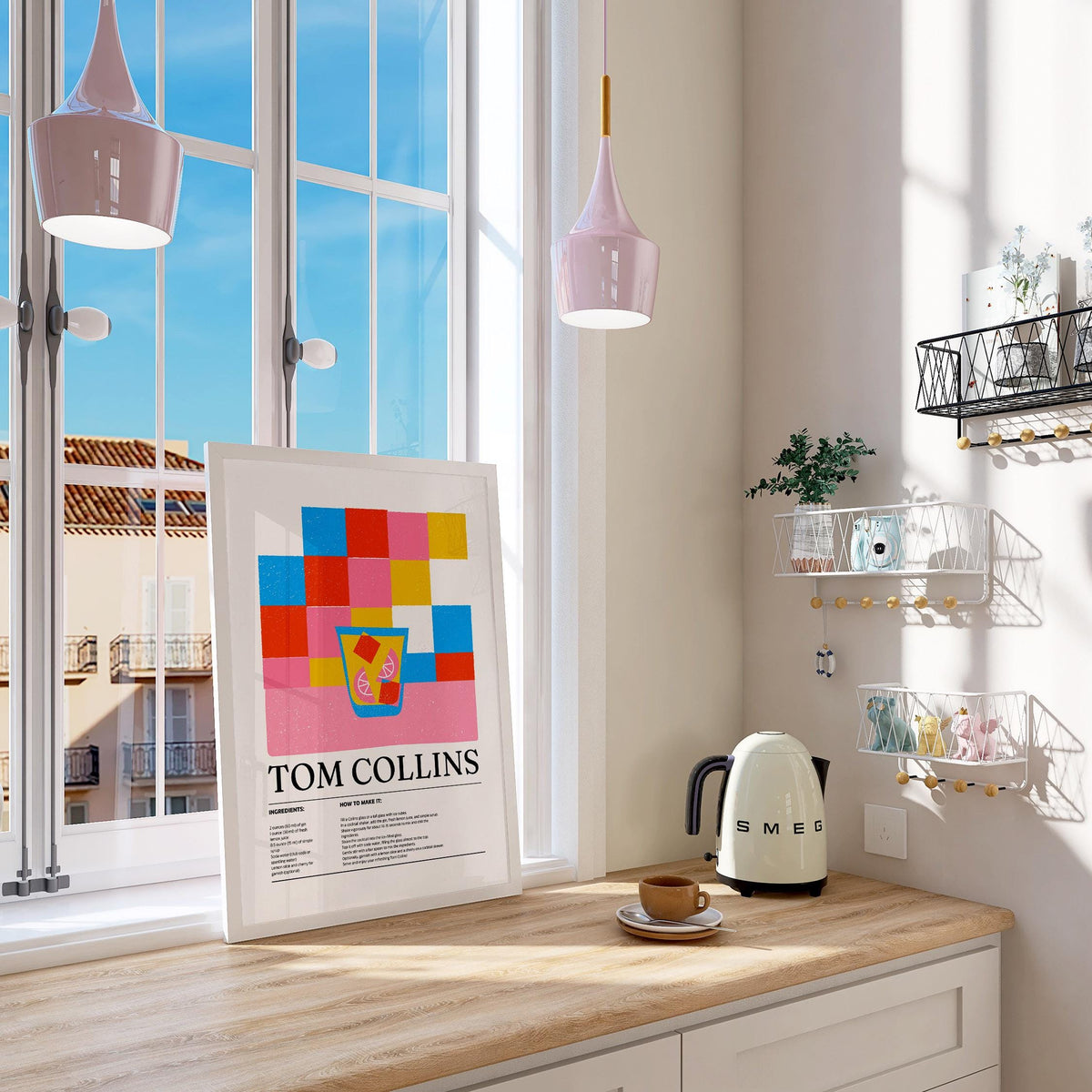 Print leaning on a kitchen counter showing colorful blocks and a Tom Collins cocktail with a SMEG kettle nearby