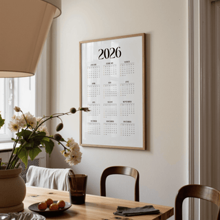 Minimalist wall calendar hung on a wall in a dining room with wooden chairs and a table