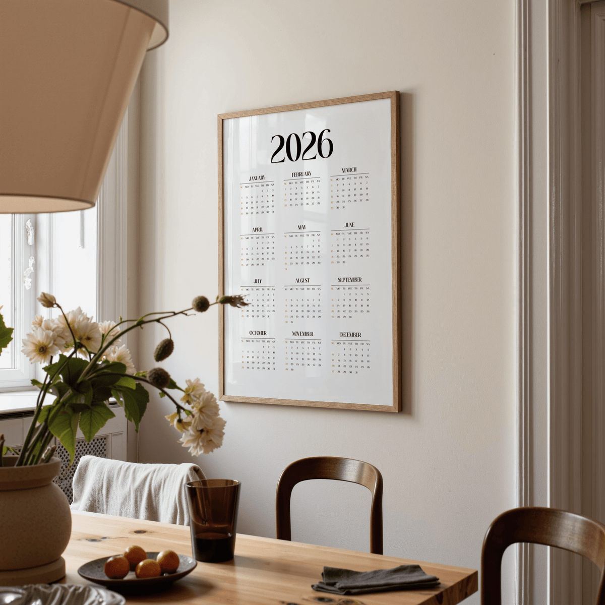 Minimalist wall calendar hung on a wall in a dining room with wooden chairs and a table