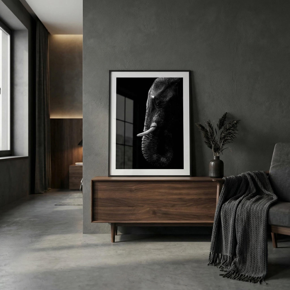 Black Elephant wall art in black and white resting on a wooden sideboard next to a vase with pampas grass