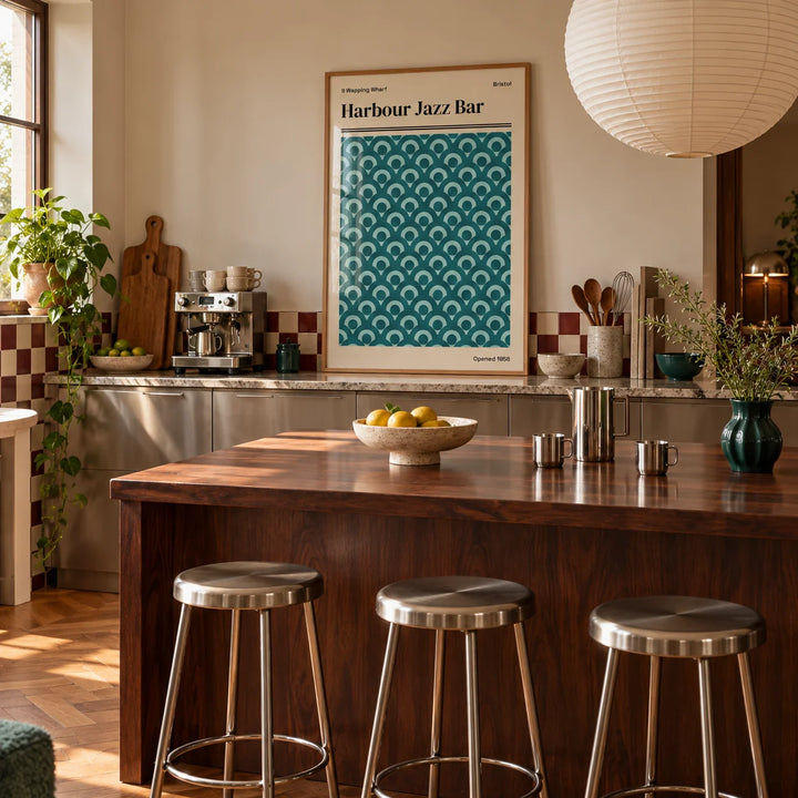 Bristol Print, framed on the wall of a warm kitchen with a burgundy and cream checkerboard tile splashback and brushed steel cabinets