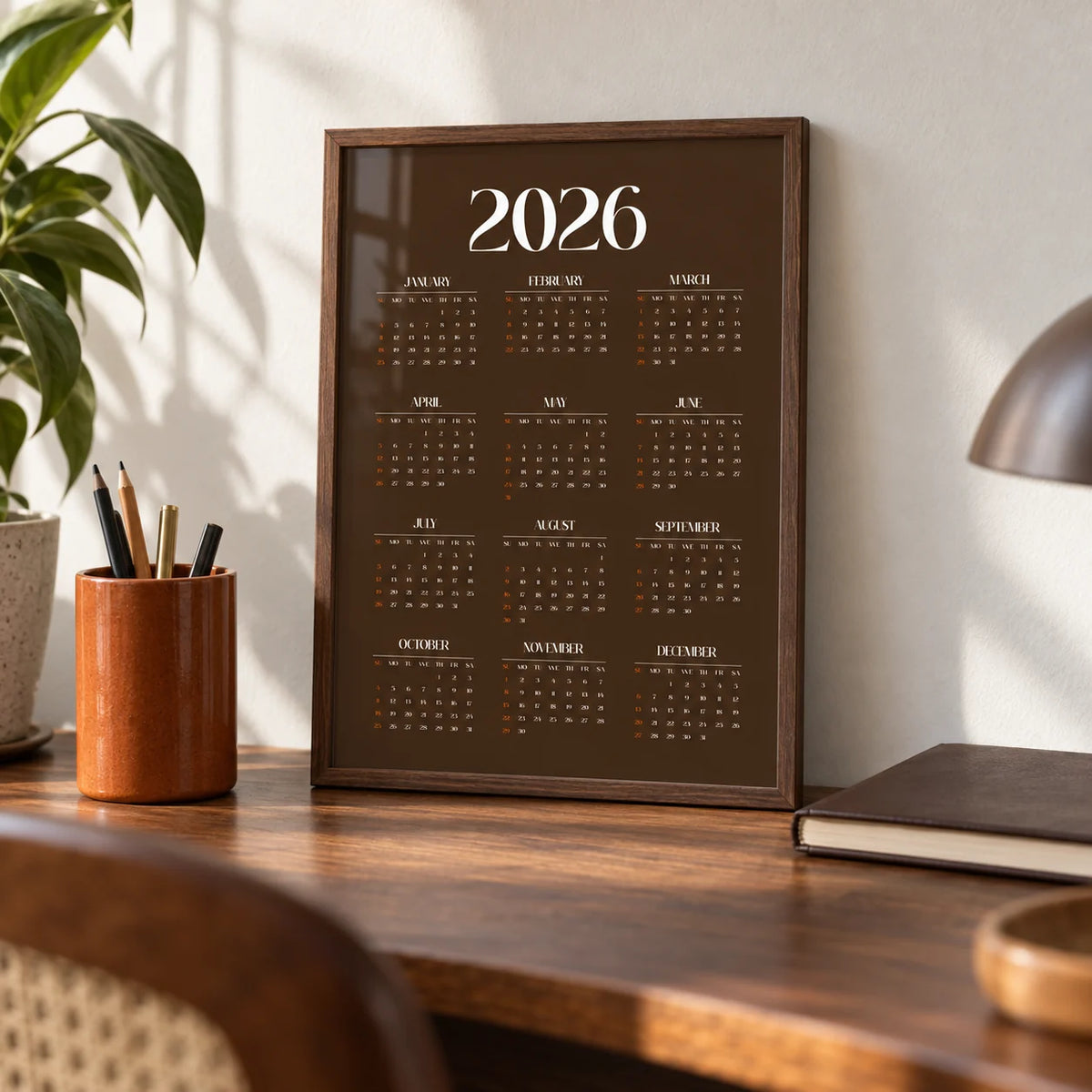 Brown Calendar Print, a small A4 framed print leaning on a walnut writing desk