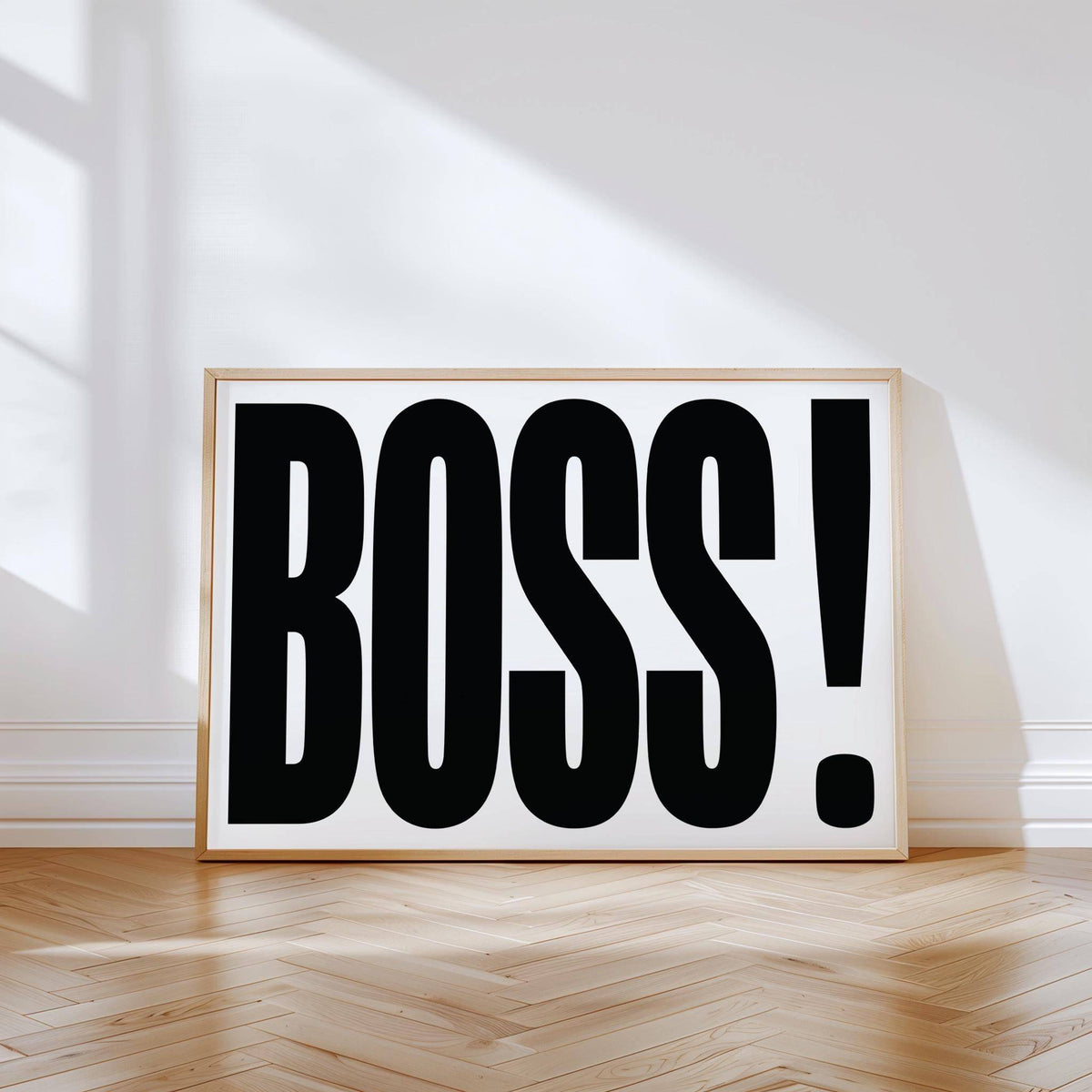 Office wall art with boss typography in black and white leaning on the floor with sunlight