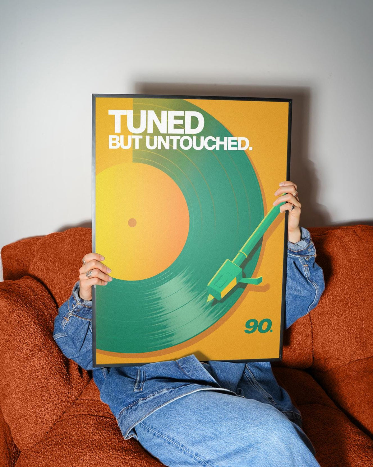 Framed Vinyl Record Art Print with green and orange minimalist record held by person on rust sofa