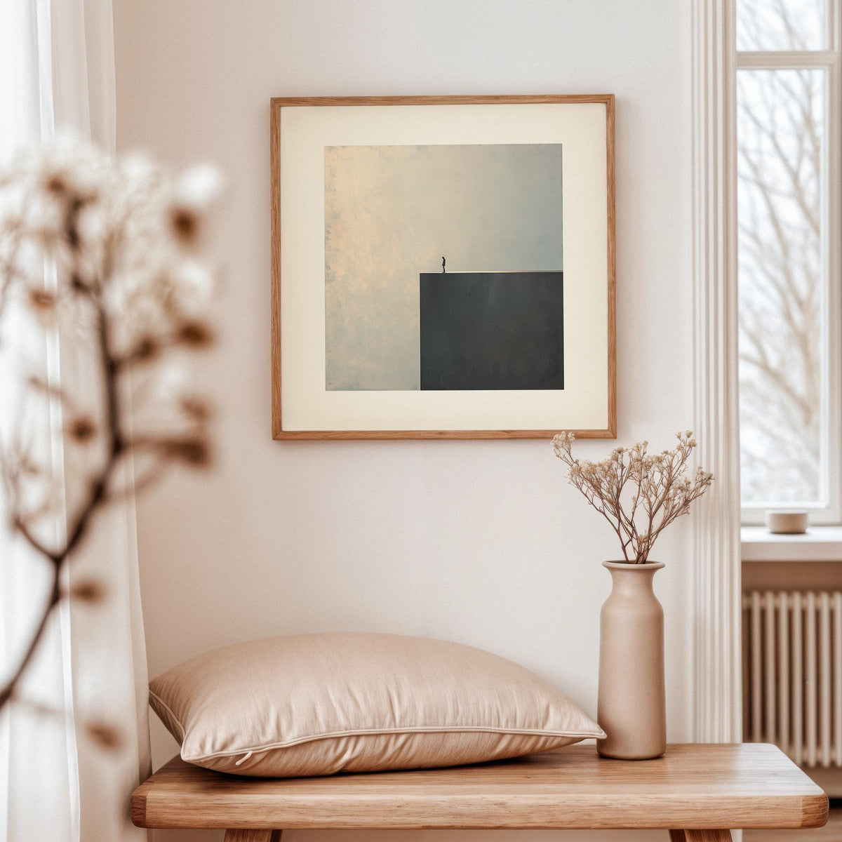 Surreal Black and White Art framed print of a person standing on a cliff edge in neutral tones with dried flowers on a wooden surface