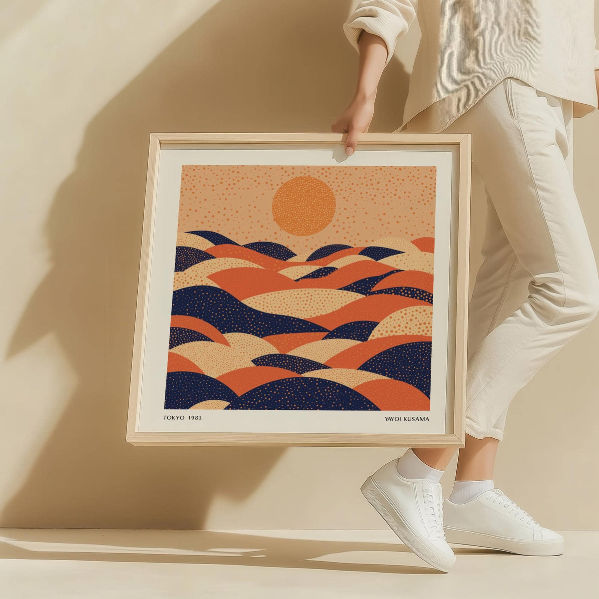 Abstract wall art colourful with orange sun and blue and beige dotted hills held by a person